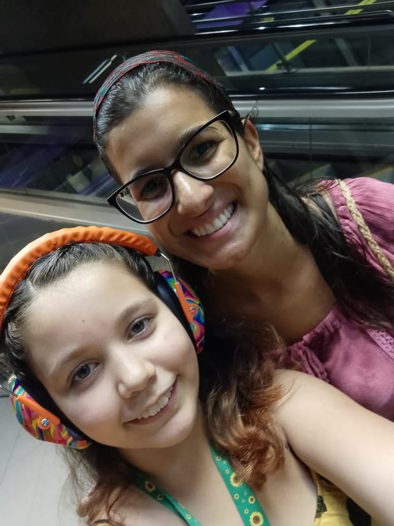 Thais Azevedo com uma criança que usa fones de cancelamento de ruído
